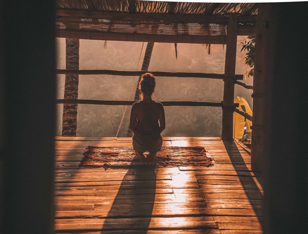 woman meditating in yoga shala with sun peeking in
