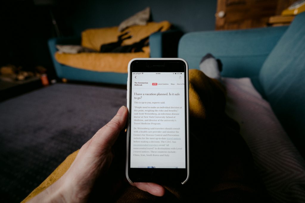 Reading about travel safety on phone during covid outbreak. Photo by Annie Spratt on Unsplash