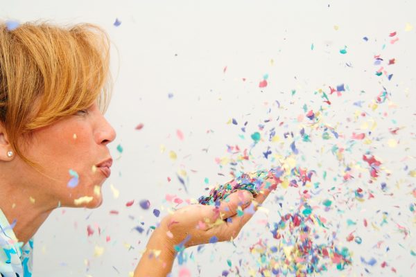 woman blowing confetti celebration of happiness